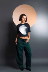 Jean de corte holgado y tiro medio, color verde oscuro, con costuras frontales verticales y diseño de paneles laterales. Cuenta con cierre de botón y bragueta, y presillas para cinturón.