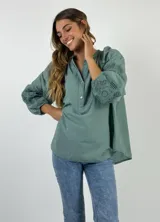 Blusa color verde agua con cuello mao y mangas largas abullonadas con detalle de encaje.