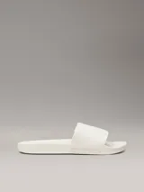 Ojotas Calvin Klein con tira ancha de tejido jacquard que presenta el logo de la marca en relieve. Poseen plantilla ergonómica moldeada con soporte para el arco y suela de EVA.