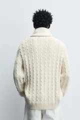 Jersey de punto de algodón con diseño de trenzas verticales, cuello redondo y manga larga con terminaciones en rib.