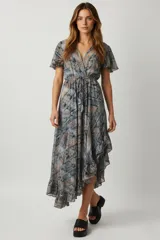 Vestido midi de poliéster con estampado paisley en tonos azules, grises y rosados. Presenta escote en V cruzado, mangas cortas con volados y cintura ajustable con lazo. La falda es asimétrica con volados en el ruedo.