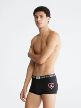 Bóxer tipo trunk de talle bajo, color negro, confeccionado en mezcla de poliéster reciclado y elastano. Presenta cintura elástica jacquard con el texto "LOVE ALL WAYS CALVIN" y el logo CK. En la parte frontal tiene un estampado de corazón con el logo CK en el interior.