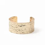Brazalete rígido abierto de metal dorado con textura irregular y acabado martillado.
