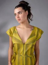 Vestido largo de lino y algodón con diseño de rayas verticales en tonos mostaza y verde. Presenta escote en V, cuello solapa ancho, mangas cortas con diseño capa, corte recto y lazo ajustable en la cintura.