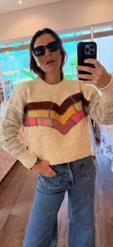 Sweater tejido en lana color crema con apliques de cuero bordados a mano en forma de chevron en tonos marrón, amarillo y rosa.