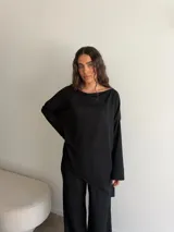 Conjunto gris melange compuesto por un buzo de cuello bote amplio y corte asimétrico con bolsillos, y un pantalón largo de corte recto y holgado.