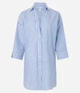 Salida de playa tipo camisa confeccionada en voile de algodón BCI con estampado de rayas verticales, cuello camisero, mangas largas y abotonado delantero.