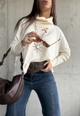 Sweater de punto color natural con cuello polera, manga larga y diseño holgado.