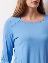 Remera blanca de modal con cuello cuadrado y aplique de aros metálicos.