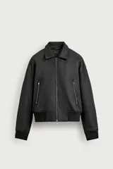 Cazadora bomber relaxed fit de Zara confeccionada en tejido efecto piel de color negro, con cuello solapa, manga larga, bolsillos delanteros con cremallera y acabados en rib elástico. Cierre frontal con cremallera metálica.