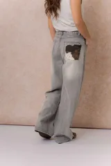Jean wide leg de tiro alto color gris con efecto lavado desgastado, corte holgado, diseño de cinco bolsillos y cierre frontal con botón y cremallera.