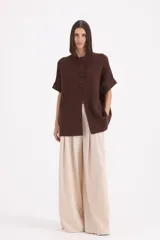 Saco de punto color chocolate, con cuello redondo, cierre frontal de tres botones y mangas cortas con dobladillo.
