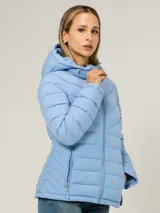 Campera puffer ligera de color celeste, con capucha y cordones ajustables, cuello alto, cierre frontal de cremallera y bolsillos laterales con cierre. Diseño acolchado con costuras horizontales y en V en el pecho.