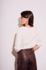 Remera de algodón color blanco roto, con escote redondo y mangas globo de tres cuartos con elástico en el puño.