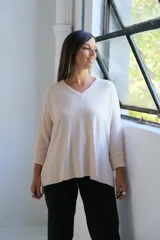 Sweater de punto en color crudo, con escote en V, mangas tres cuartos con puños acanalados y diseño holgado.