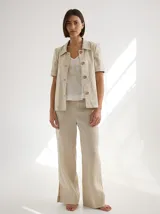 Chaqueta de lino color beige, con cuello camisero, manga corta y cierre frontal con botones de madera.