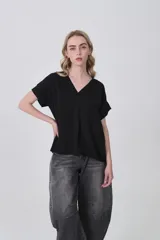 Blusa negra de poliéster con cuello en V, corte holgado y detalle de pinza central en el frente. Posee mangas cortas con dobladillo.
