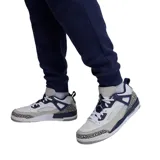 Pantalon de jogging Nike Jordan, confeccionado en tejido fleece color negro, con cintura elástica ajustable mediante cordón, puños elásticos en los tobillos y logo Jumpman bordado en color rojo en la pierna izquierda.