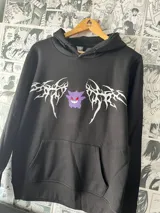Canguro negro con capucha y bolsillo delantero. Estampado frontal con el personaje Gengar de Pokemon y diseños tribales en blanco.