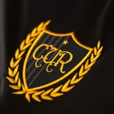 Camiseta de fútbol Puma de manga larga, edición aniversario del Club Atlético Peñarol. Diseño combinado en negro y amarillo, con cuello polo, rayas verticales en el lateral derecho y el lado izquierdo liso, incorporando detalles y sponsors en color dorado.