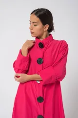 Camisola fucsia con cuello mao, mangas largas con puños y cierre frontal con botones grandes negros.