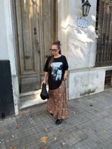 Conjunto compuesto por un remerón negro de algodón con estampa fotográfica frontal y una pollera midi de satén con estampado animal print de leopardo.