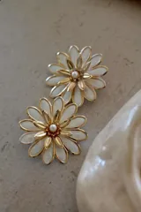 Par de aros con forma de flor, con pétalos blancos y centro dorado con una perla.