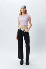 Top corto ajustado color lila claro, con cuello redondo y mangas cortas. Presenta costuras verticales marcadas en el frente.