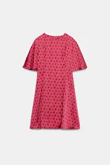 Vestido corto de cuello redondo y manga corta fluida, con cierre de cremallera oculta en la espalda. Presenta un estampado geométrico de círculos en tonos rosados y marrones.