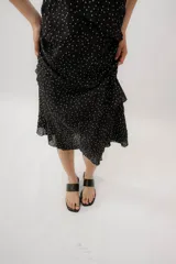 Vestido midi negro con estampado de lunares blancos, escote en V, breteles finos y diseño con volados en capas.