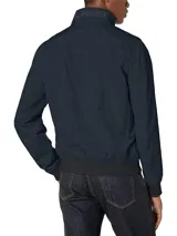 Campera bomber Tommy Hilfiger azul marino con cuello alto, cierre frontal con cremallera, dos bolsillos laterales con cremallera, puños y bajo elásticos. Tiene el logo de Tommy Hilfiger bordado en el pecho y un parche con el logo en la manga izquierda. El interior del cuello tiene detalles en rojo, blanco y azul.