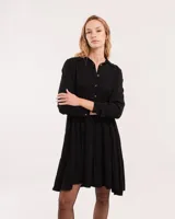 Vestido corto marrón con cuello camisero, abotonado en el frente, mangas largas con elástico en los puños y falda escalonada con volados.