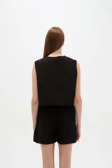 Chaleco negro de algodón sin mangas, con escote en V y bordados detallados.