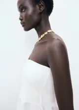 Top peplum blanco sin mangas, con escote palabra de honor y diseño ajustado en el torso con vuelo en el bajo.