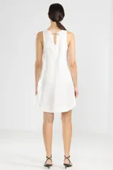 Vestido corto blanco de lino italiano con fibra metalizada, corte holgado y sisas amplias. Presenta cortes redondeados a los costados y la insignia de tigre Polonio en la espalda.