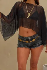 Poncho corto de lurex negro transparente, con diseño asimétrico y mangas amplias tipo capa.
