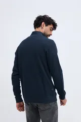 Buzo de felpa diferenciada azul marino con cuello alto y medio cierre frontal, de manga larga y puños elásticos.