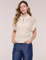 Buzo de punto color marfil, confeccionado en algodón calado con cuello alto acanalado y medio cierre metálico dorado. Presenta mangas cortas estilo japonesa con puños anchos y un zócalo acanalado en el ruedo.