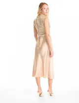 Vestido midi de satén color champagne con corte al bies y escote recto, acompañado por un top sin mangas de cuello alto cubierto de lentejuelas doradas con detalle drapeado en la cintura.