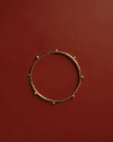 Brazalete esclava rígido bañado en oro, decorado con pequeñas esferas distribuidas a lo largo de su circunferencia.