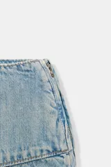Falda midi de denim en tono azul claro, con tiro medio y diseño asimétrico con tablas laterales. Cuenta con cierre lateral mediante cremallera metálica.