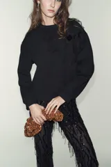 Sudadera de algodón con cuello redondo y manga larga, caracterizada por un detalle de flor con volumen confeccionada en organza sobre el hombro. Presenta terminaciones en rib en puños y ruedo.