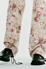 Jeans rectos de tiro medio con estampado floral multicolor sobre base blanca, trabillas para cinto, bolsillos delanteros y cierre frontal con cremallera y botón metálico.