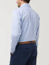 Camisa de manga larga en tejido oxford color celeste claro, con cuello abotonado, bolsillo en el pecho y cierre frontal con botones.