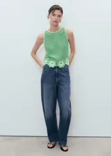 Top sin mangas verde de punto medio con cuello redondo y diseño recto. Presenta un detalle de bajo con acabado floral bordado y calado.