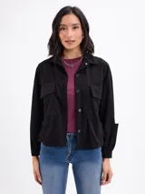 Campera de pana negra con cierre frontal de botones metálicos, cuello clásico y dos bolsillos frontales con solapa. Presenta mangas largas con puños abotonados y un diseño liviano sin forro.