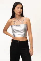 Crop top ajustado de napa fina color plateado, con breteles ajustables y diseño de tiras cruzadas en el escote. Presenta pinzas en la parte delantera y zona elástica en la espalda.