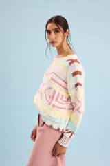 Buzo oversize de punto color marfil con diseño geométrico jacquard en tonos rosado, amarillo, celeste y marrón. Cuenta con cuello redondo y mangas largas.
