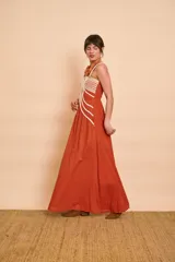 Vestido largo color terracota de tirantes, con detalles de cordones decorativos en color crudo en la parte frontal y falda amplia de corte fluido.