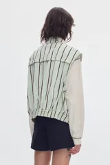Chaleco oversize de denim color crudo con estampado de lunares negros, cuello camisero, bolsillos delanteros y cierre frontal de botones metálicos.